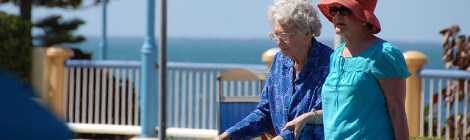 two women crossing beachside road, one using a walker
